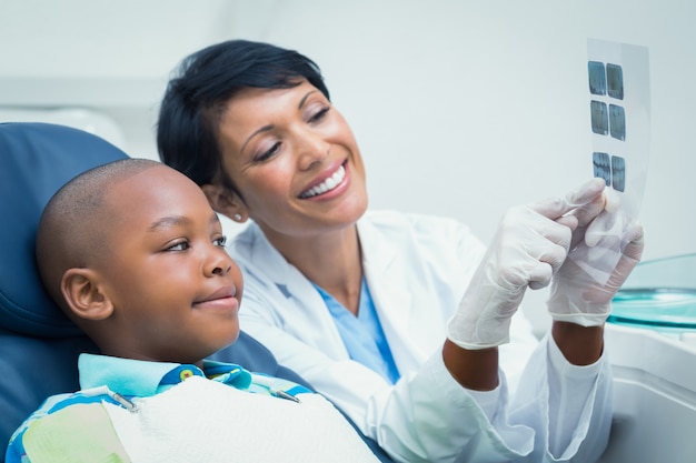 Dentista femenino que muestra al muchacho su boca radiografía