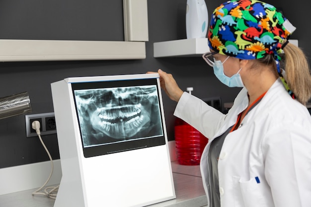 Foto dentista femenino viendo una radiografía dental de un paciente