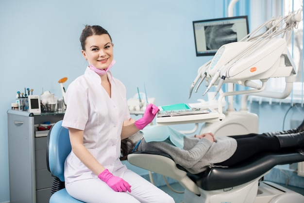 Dentista feminina amigável com paciente no consultório odontológico