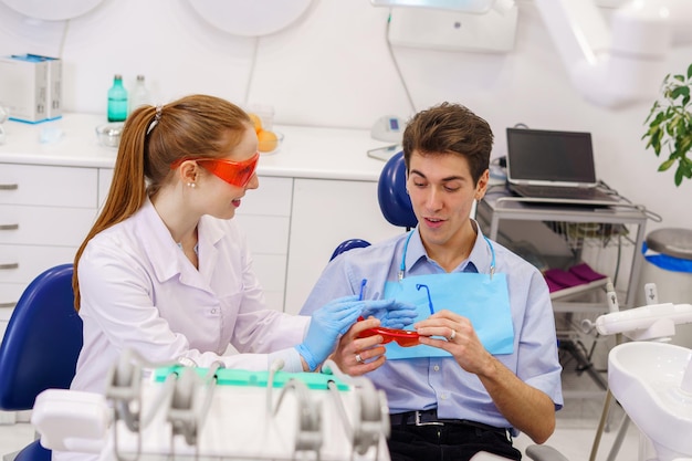 Dentista feminina dando óculos para paciente do sexo masculino