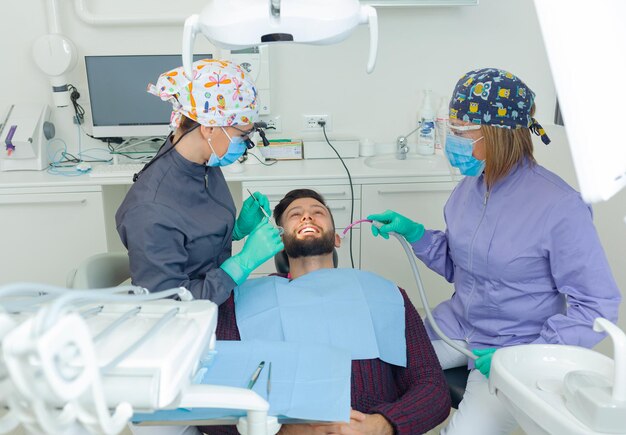 Dentista feminina examina um paciente homem em um consultório odontológico