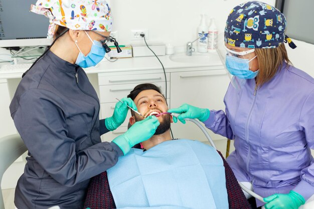 Dentista feminina examina um paciente homem em um consultório odontológico