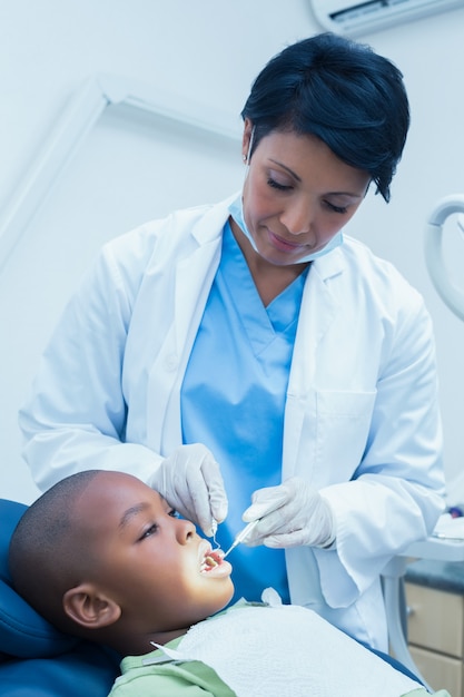 Dentista feminina examinando os dentes de meninos