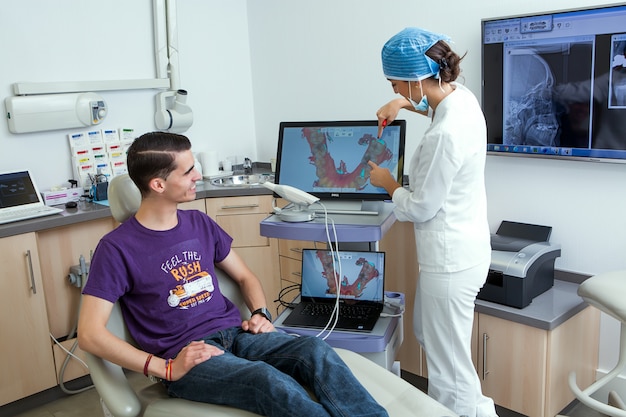 Dentista feminina mostrando dentes digitalizar para um cliente sorridente