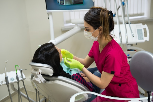 Dentista feminina no trabalho, examinando os dentes da mulher na clínica odontológica