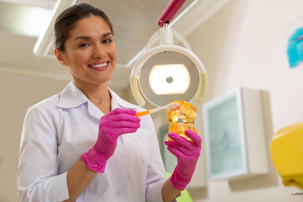 Dentista feminina sorridente em luvas assépticas, olhando para a câmera