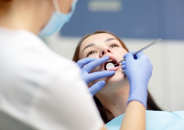 Dentista feminina, verificando os dentes da mulher do paciente