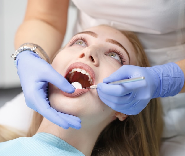 Dentista feminina, verificando os dentes da mulher do paciente