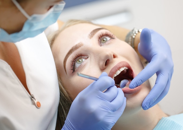 Dentista feminina, verificando os dentes da mulher do paciente