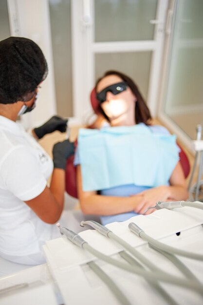 Dentista feminina verificando os dentes do paciente com aparelho no consultório da clínica odontológica medicina odontologia co