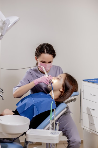Dentista feminina verificando os dentes do paciente no consultório da clínica odontológica. Medicina, conceito de odontologia. Equipamentos odontológicos.