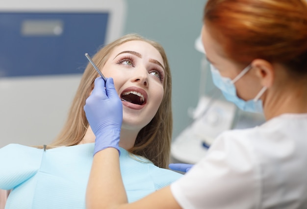 Dentista feminina, verificando os dentes do paciente