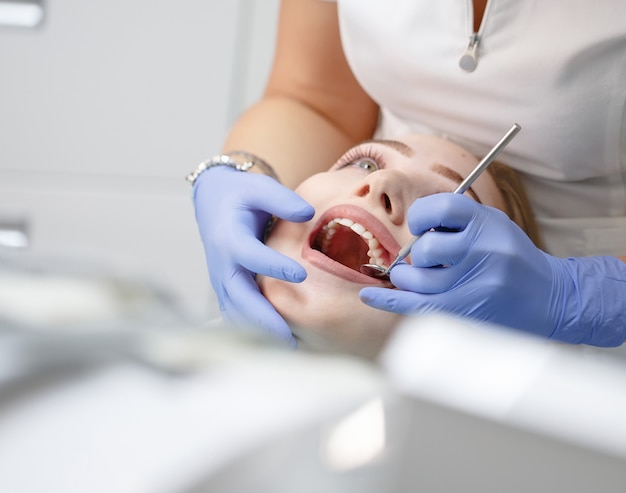 Dentista feminina, verificando os dentes do paciente