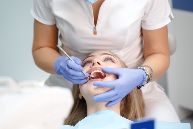 Dentista feminina, verificando os dentes do paciente