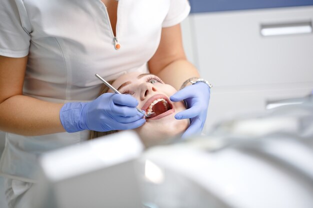 Dentista feminina, verificando os dentes do paciente