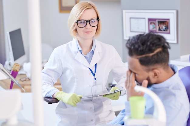 Dentista feminino amigável, ouvindo o paciente