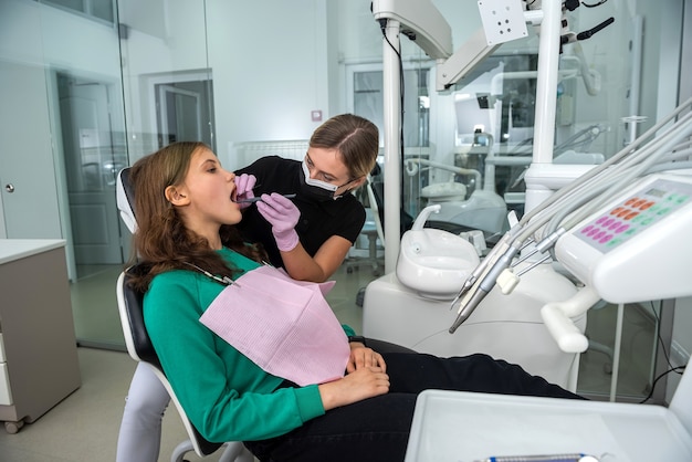 Dentista feminino se preparando para o paciente jovem exame odontológico. dentes saudáveis