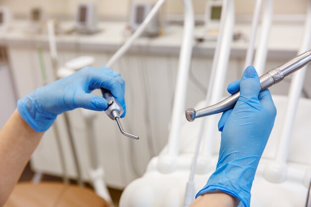 Dentista con guante sostiene un instrumento o instrumento manual de diagnóstico