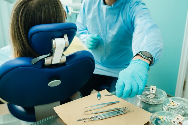 Un dentista con guantes en el consultorio dental sostiene una herramienta antes de trabajar.