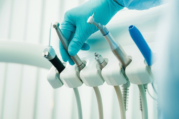 Un dentista con guantes en el consultorio dental sostiene una herramienta antes de trabajar.