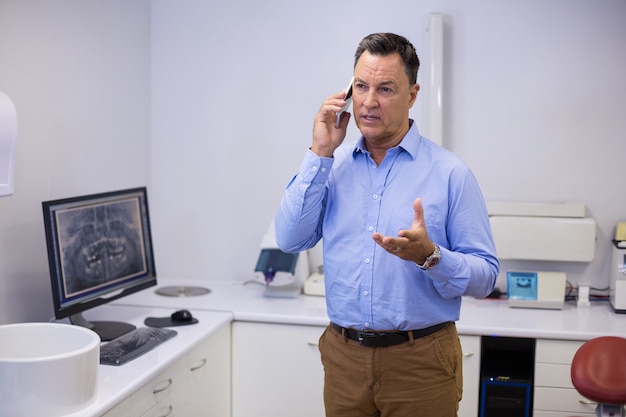 Foto dentista hablando por teléfono móvil