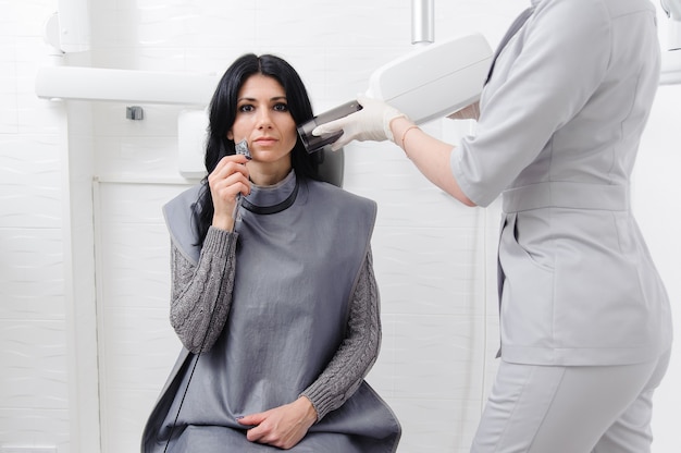 El dentista hace la imagen de rayos x de la mandíbula para la mujer en la clínica dental