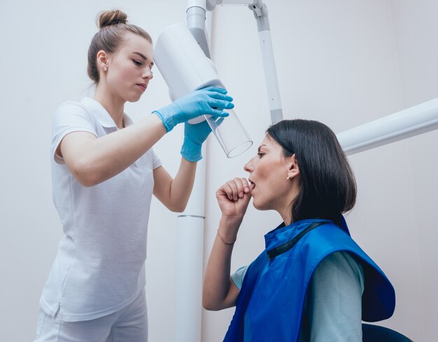 Dentista hacer una imagen de rayos x para la mujer joven en la clínica dental. Con el objetivo de radiografía dental.