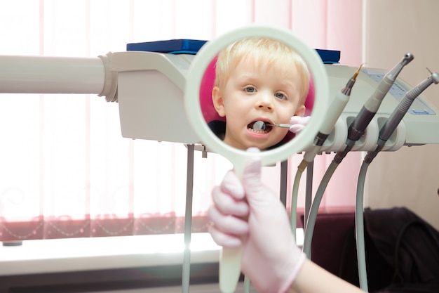 Dentista haciendo chequeo dental regular al niño pequeño.