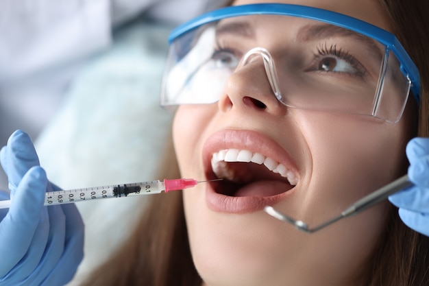 Dentista haciendo inyección en la encía del paciente en la clínica