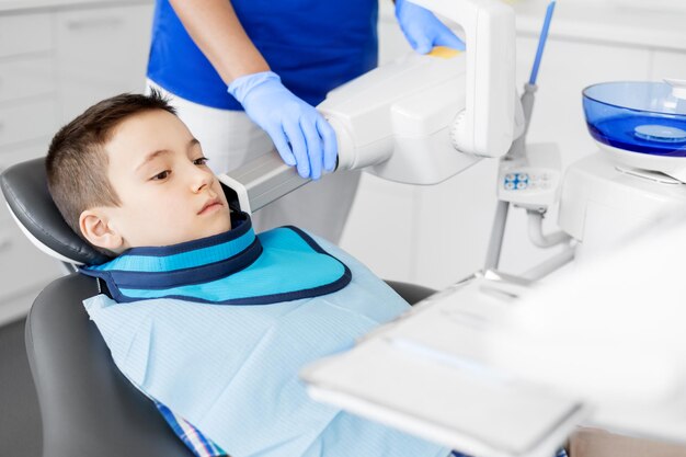 Foto dentista haciendo radiografías de dientes de niño en la clínica dental