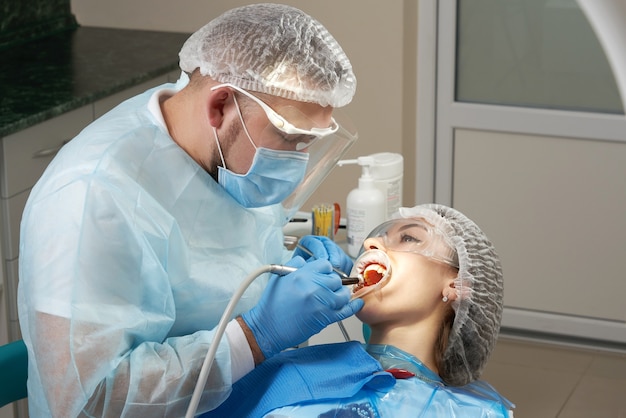 Dentista haciendo un tratamiento dental en una paciente. Dentista examinando los dientes de un paciente en moderno