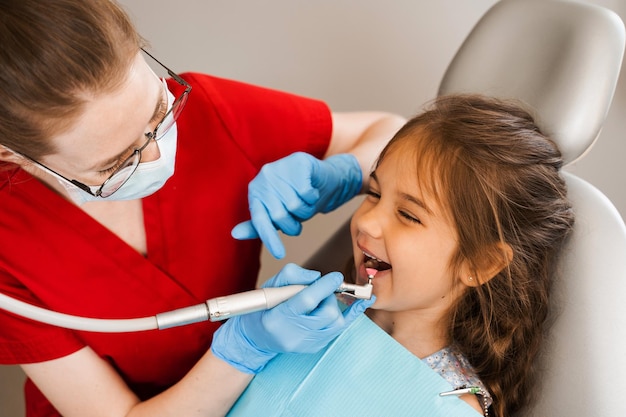 El dentista infantil realiza una limpieza dental profesional en odontología Higiene profesional para los dientes de un niño en odontología El dentista pediátrico examina y consulta a un paciente infantil en odontología