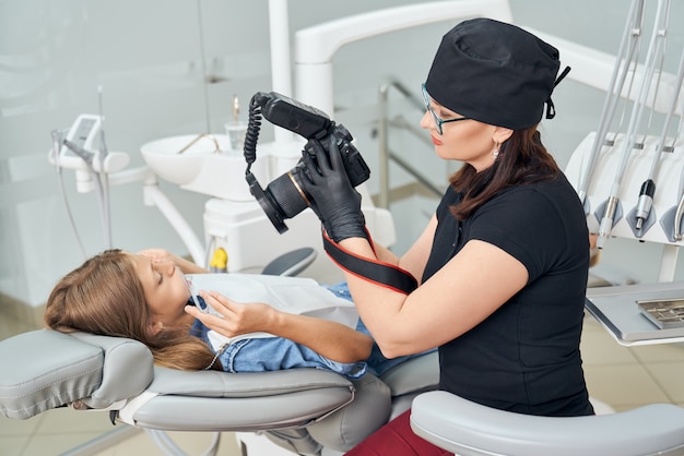 Dentista, inspecionando os dentes de jovem.