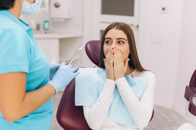 Foto el dentista inyecta anestesia a la niña paciente que tiene miedo