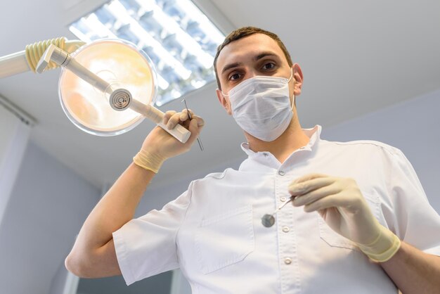 Dentista jovem em luvas de proteção e uma máscara