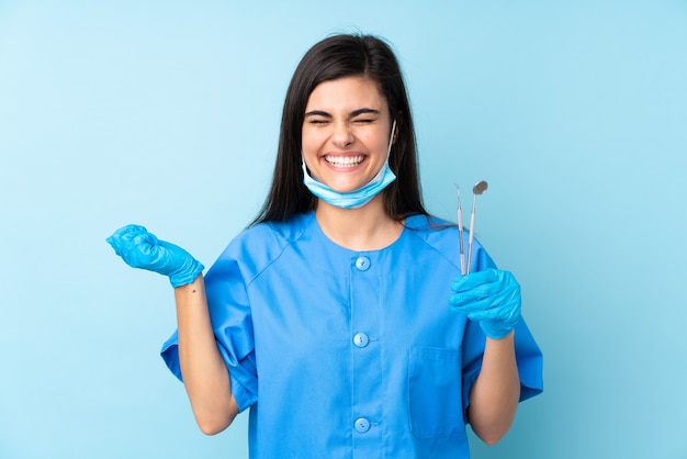 Foto dentista jovem segurando ferramentas e rindo azul isolado