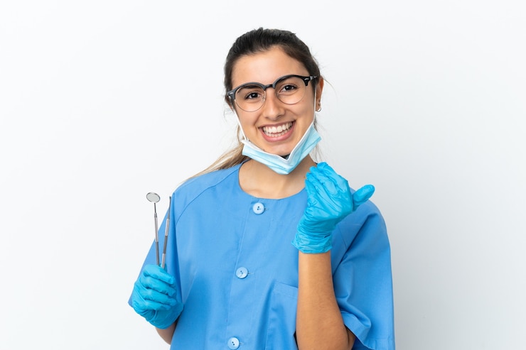 Foto dentista jovem segurando ferramentas isoladas no fundo branco, convidando para vir com a mão. feliz que você veio