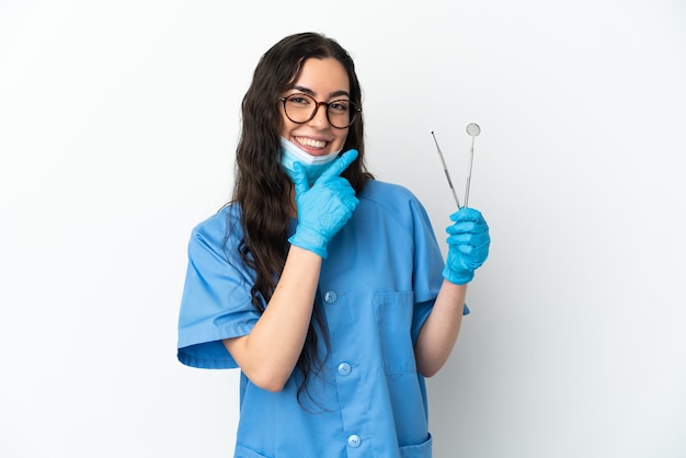 Dentista jovem segurando ferramentas isoladas no fundo branco, feliz e sorridente