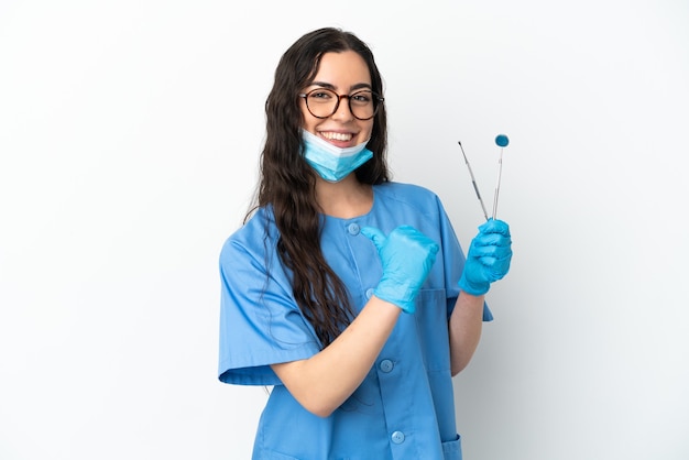 Dentista jovem segurando ferramentas isoladas no fundo branco, orgulhosa e satisfeita