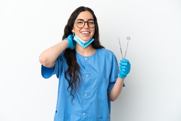 Dentista jovem segurando ferramentas isoladas no fundo branco rindo