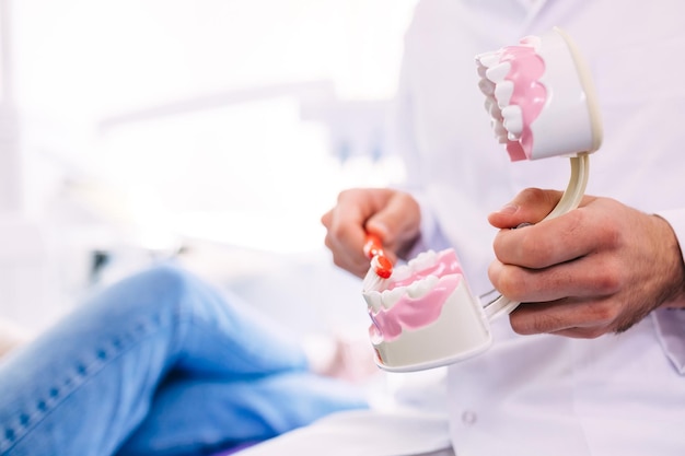 Foto un dentista joven muestra al paciente cómo cepillarse los dientes correctamente. oficina del dentista.