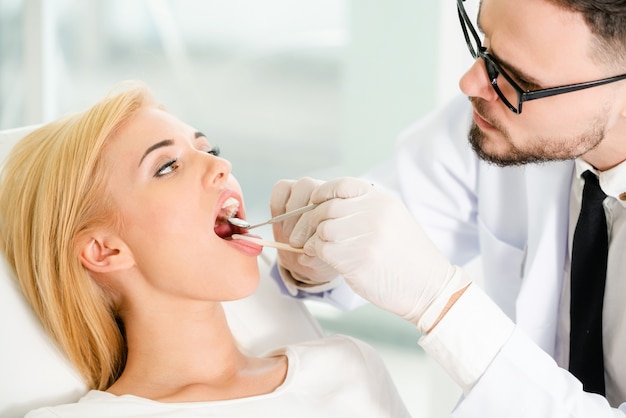 Dentista joven que examina al paciente en clínica dental.