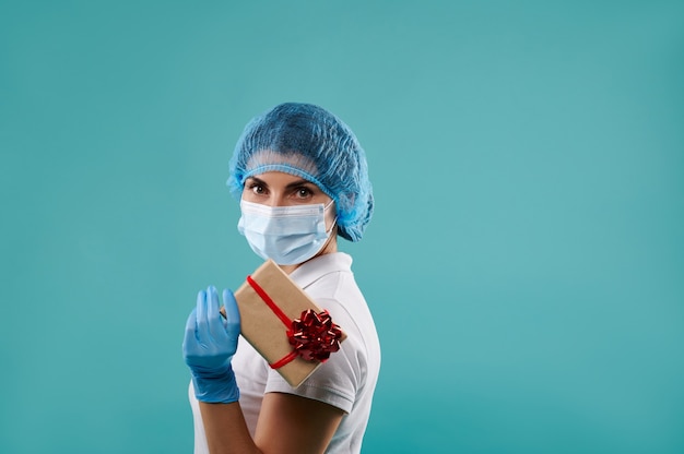 dentista joven con un sombrero y una máscara tiene un regalo de Navidad.