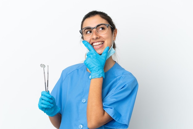 Dentista joven sosteniendo herramientas aisladas sobre fondo blanco feliz y sonriente