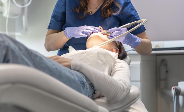 El dentista limpia la boca del paciente.