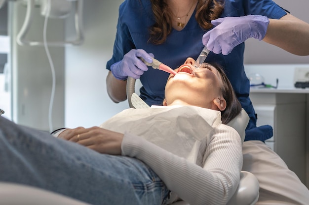 El dentista limpia la boca del paciente.