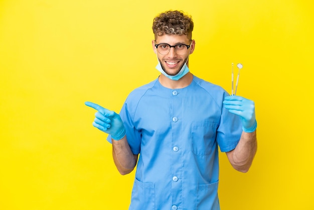 Dentista loira segurando ferramentas isoladas no fundo, apontando o dedo para o lado