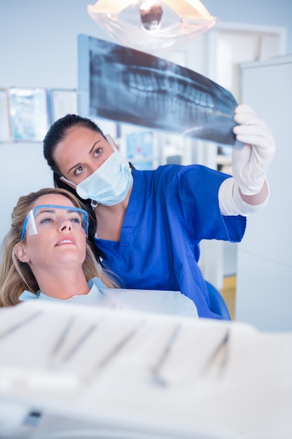 Dentista en máscara explicando rayos x al paciente