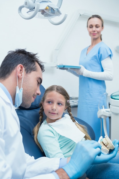 Dentista masculina ensinando menina como escovar os dentes