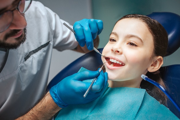 dentista masculina fazendo check-up da boca da menina